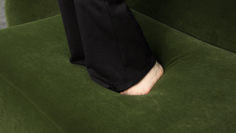 Close-up of a green plush sofa cushion compressing under pressure to show its soft, responsive cushioning.