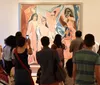 A group of people is viewing and taking photographs of a large colorful painting in an art gallery