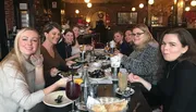 A group of people is enjoying a meal together at a restaurant with smiles and various dishes on the table.