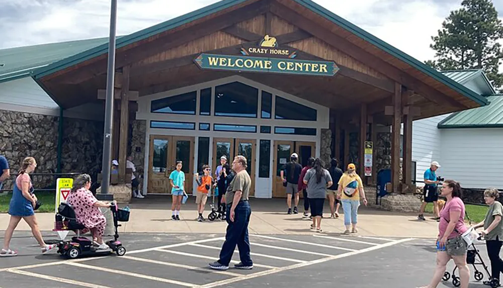 Visitors are seen arriving and departing outside the Crazy Horse Welcome Center on a sunny day