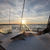 A shark lies on the deck of a boat with the sun setting over the water in the background.