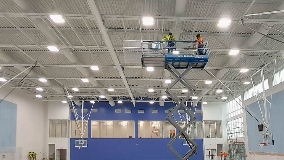 Workers inspection joist on lift in gymnasium