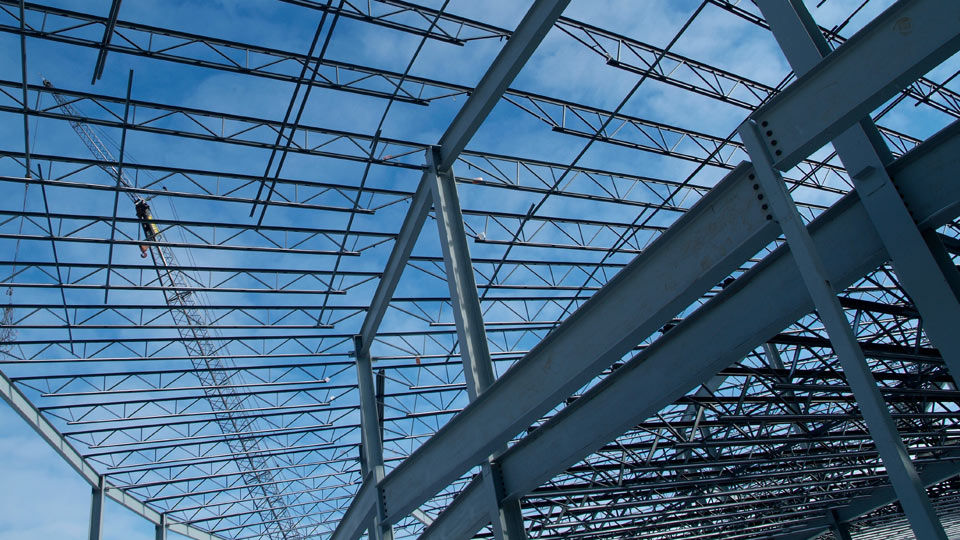 Crane lowering steel joist onto steel girder