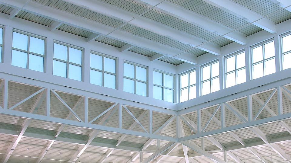 The sloping roof with diffused glass clerestory floods the pool and grandstand with natural light and provides protection from the humid and noisy environment.