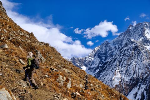 hiker climbing a hill next to a snow covered mountain