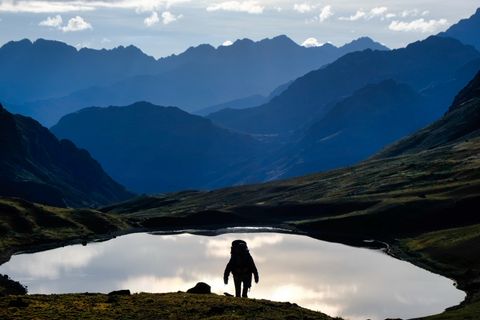 hiker silhouette walking in front of lake