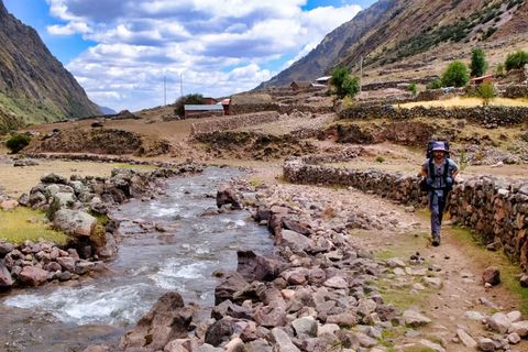 hiker walking next to river in village