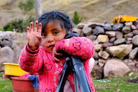 little girl holding tripod and waving