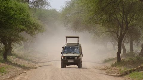 safari jeep driving through dust