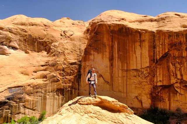 hiker standing red sandstone cliff blue sky