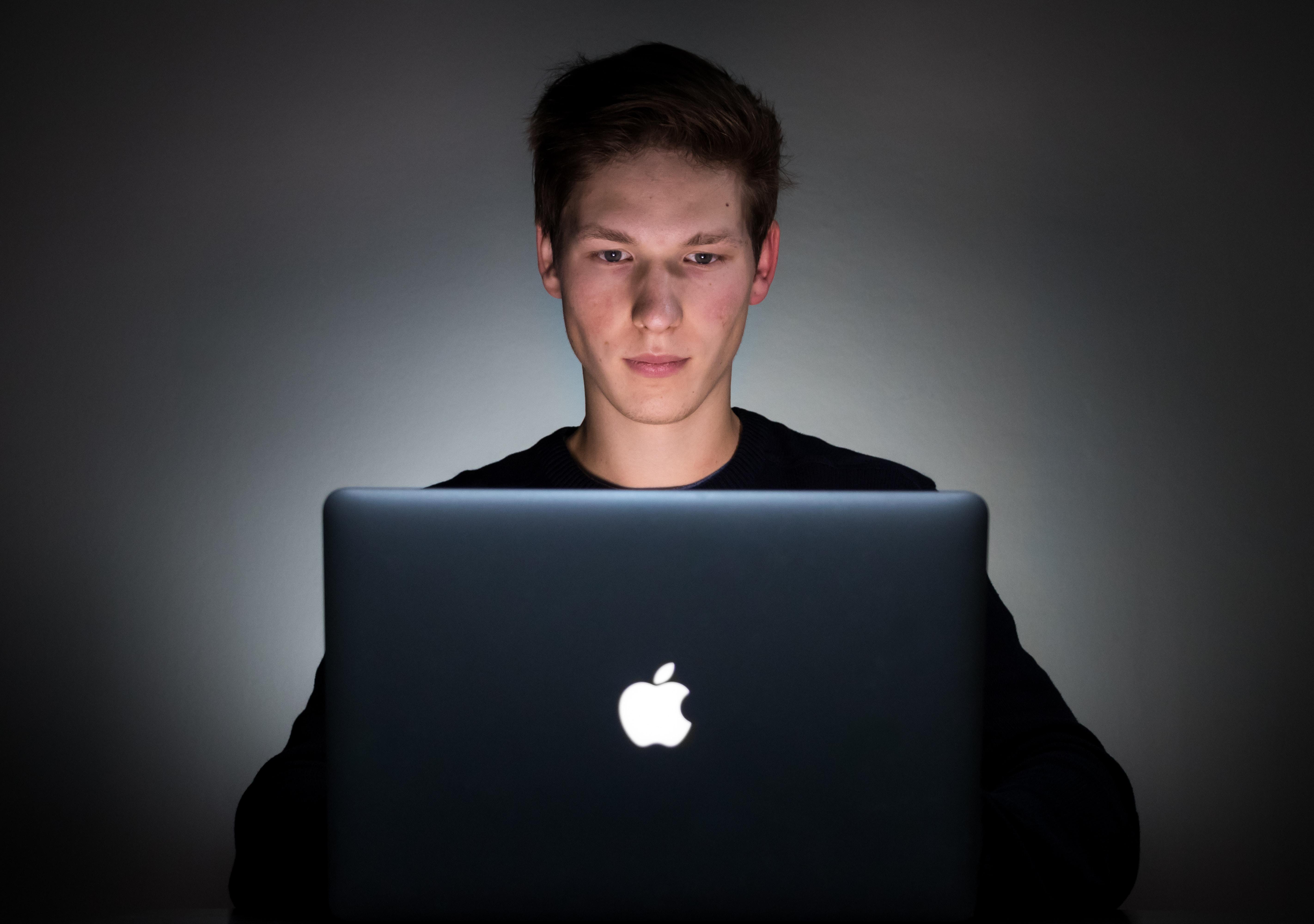 young man using a laptop computer in a dimly lit room