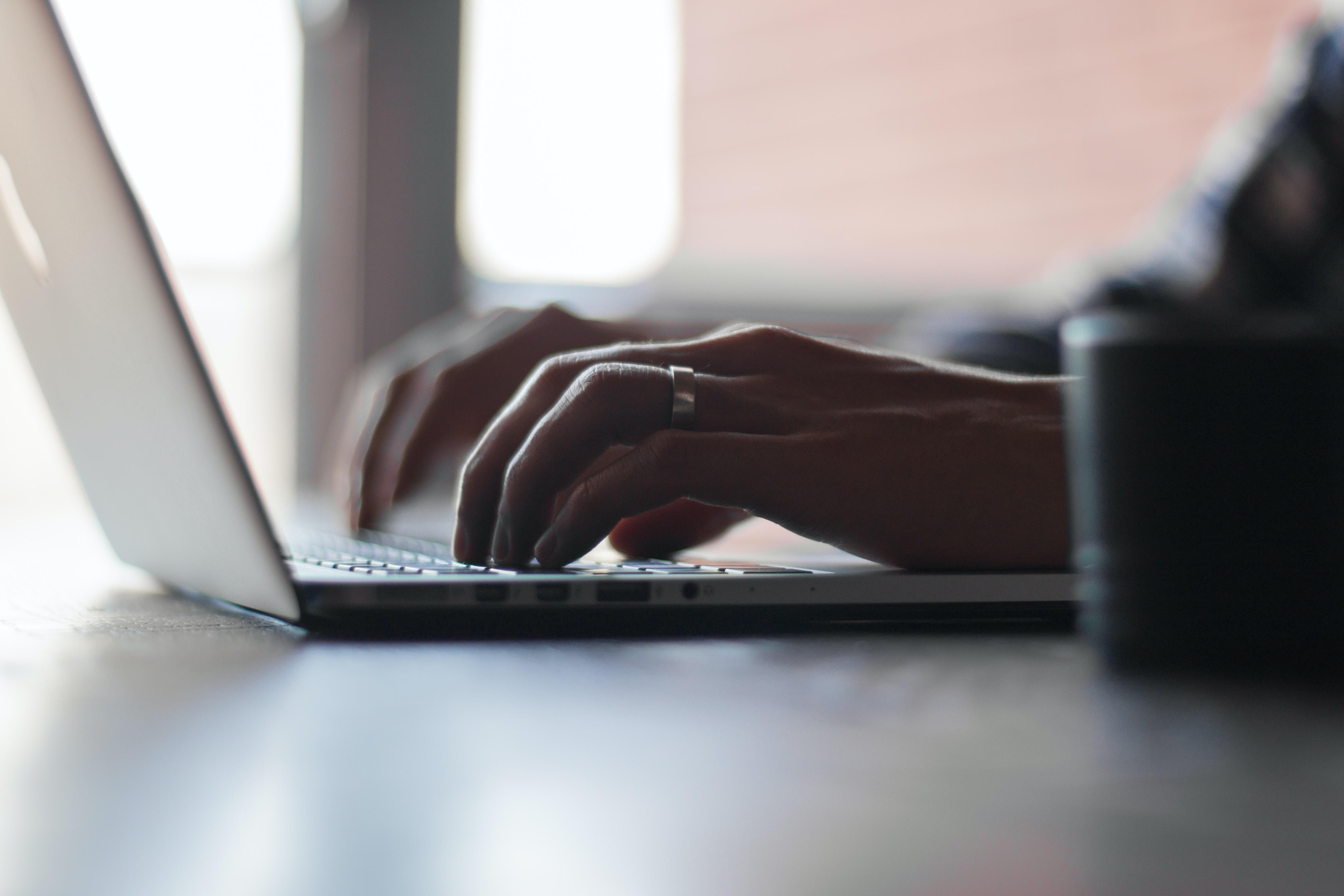 a pair of hands typing on a laptop computer