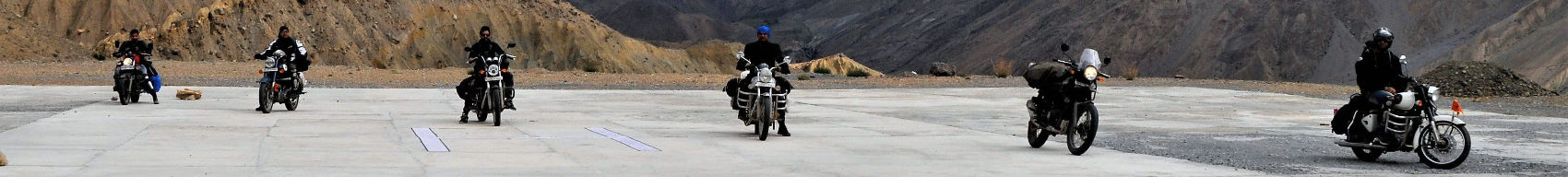 a group of 6 motorcycles riding on a road through the mountains