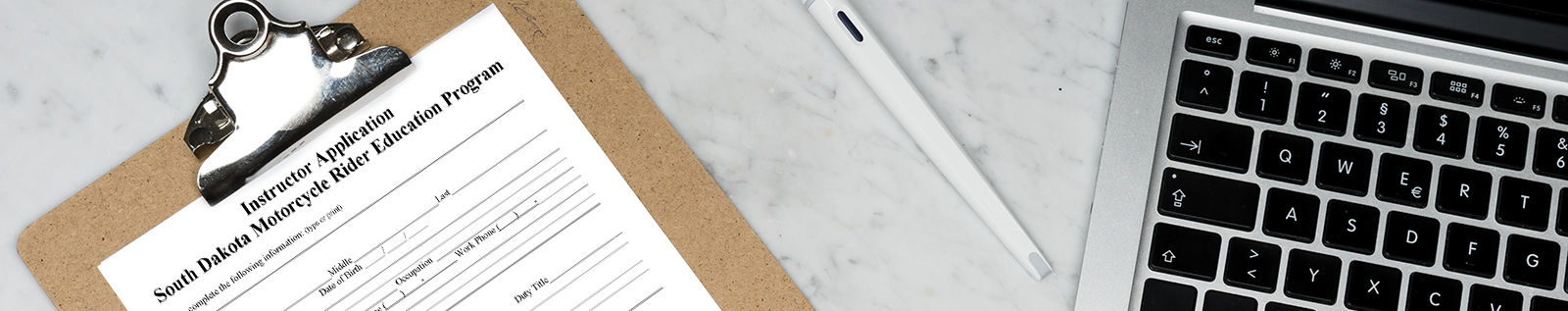 image of a clipboard with the Instructor Application on it, next to a laptop and a pen
