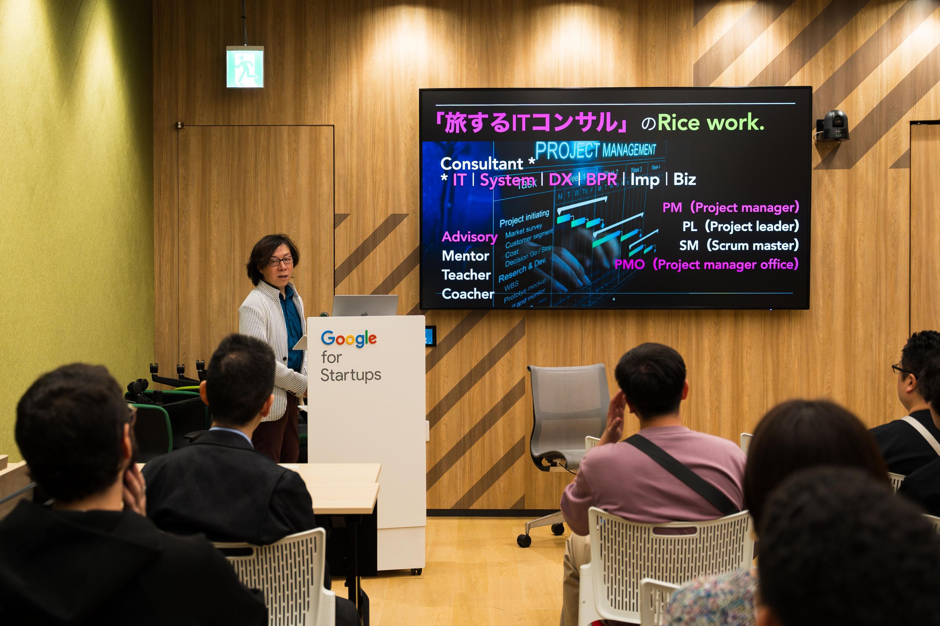 高石さんのトークの様子。右手のスクリーンには、「旅するITコンサルのRice Work」という見出しで仕事の内容を紹介しているスライドが映っている
