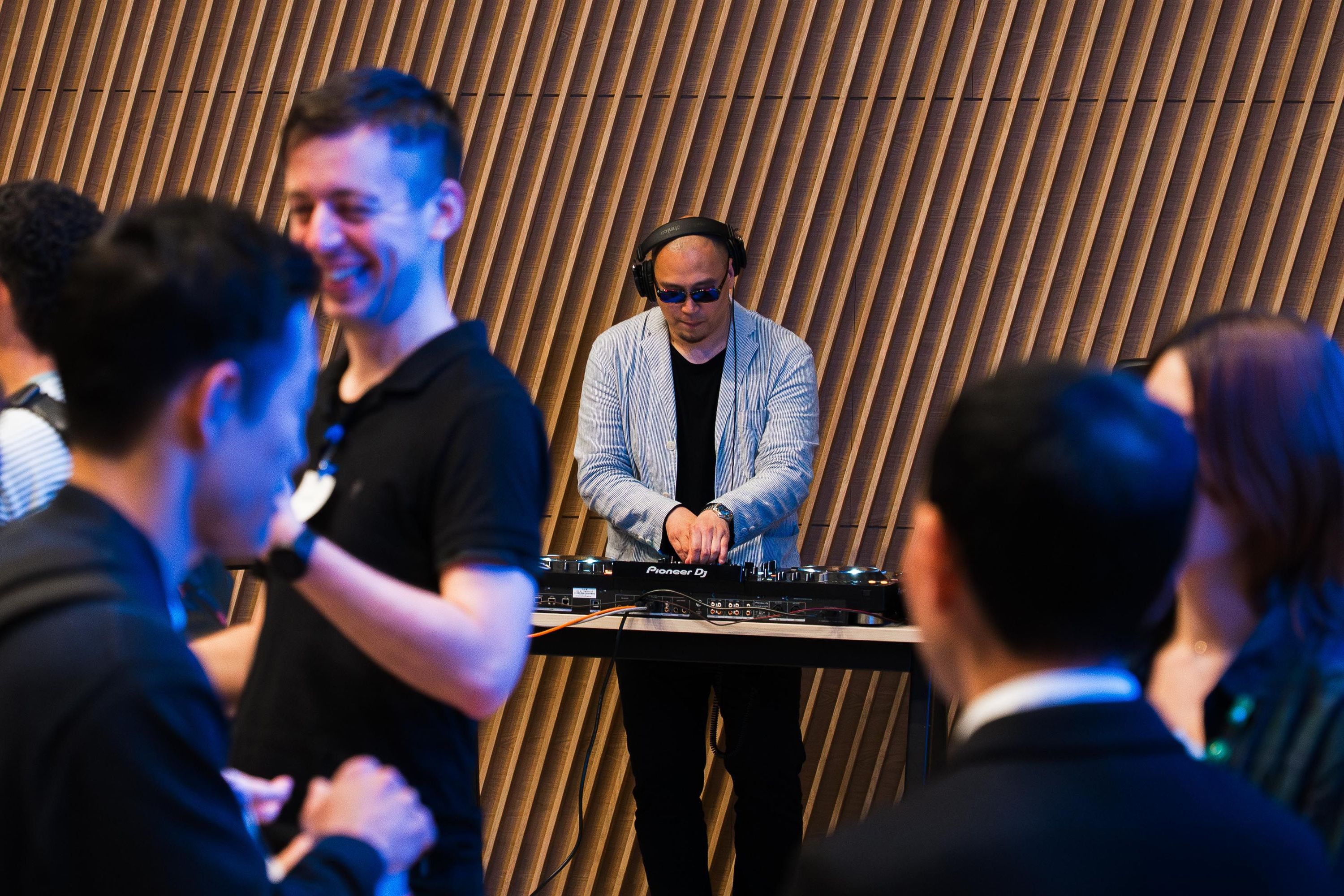 DJがプレイしている様子。手前には談笑する人々が映っている