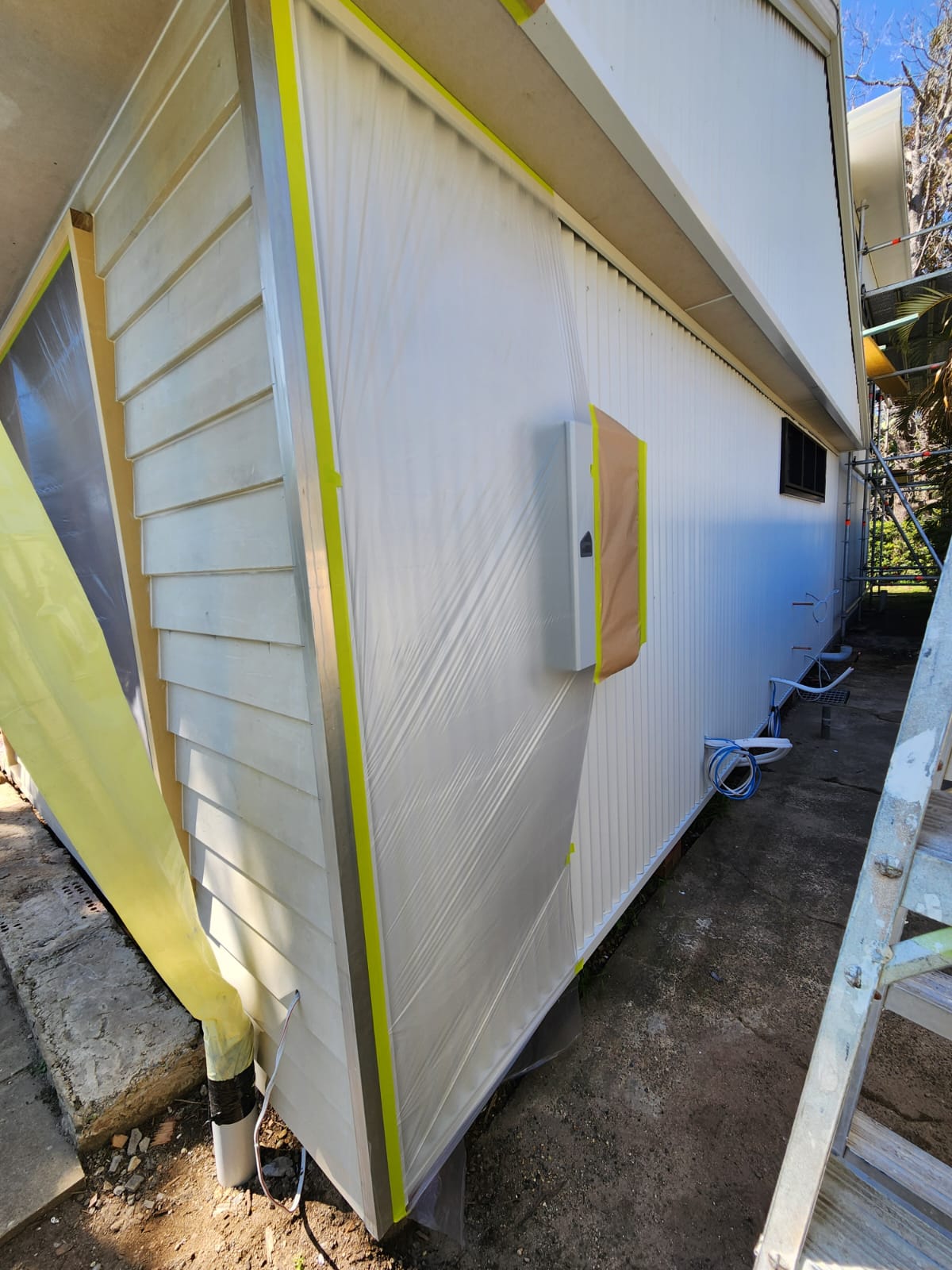 Exterior weatherboard wrapped in plastic sheeting during preparation