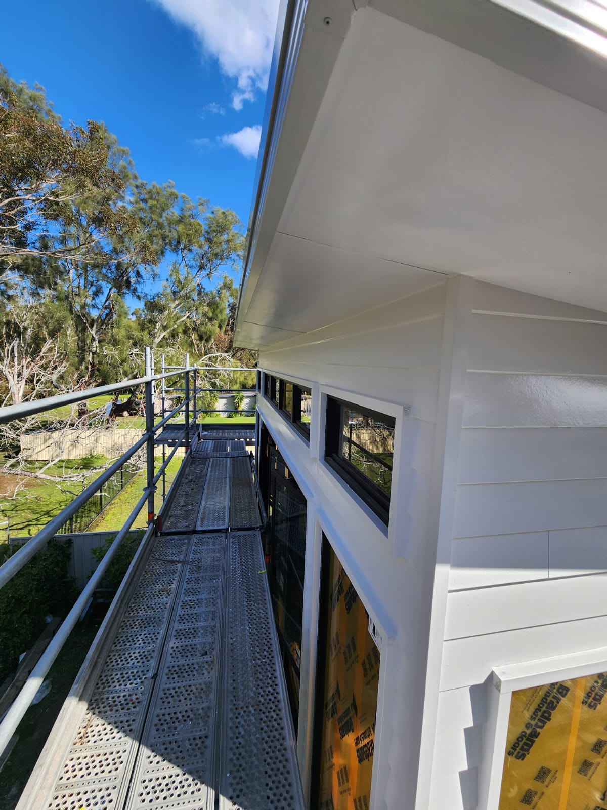 Freshly painted white eaves and weatherboard viewed from scaffolding