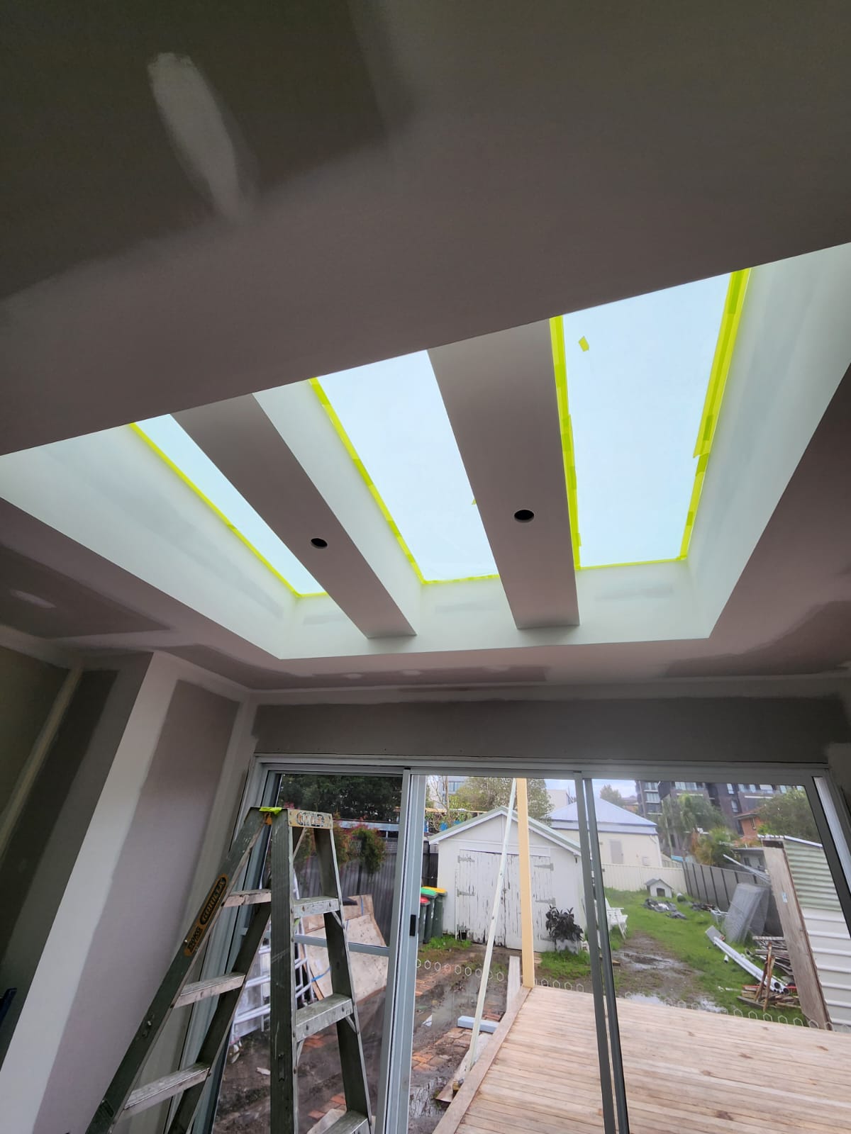 Interior ceiling with skylights masked and ladders set up for painting