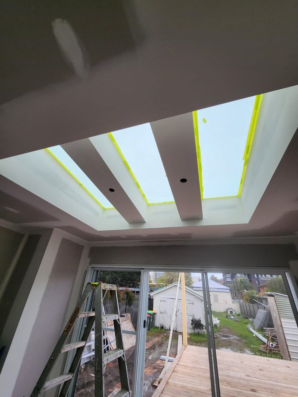 Interior ceiling with skylights masked and ladders set up for painting