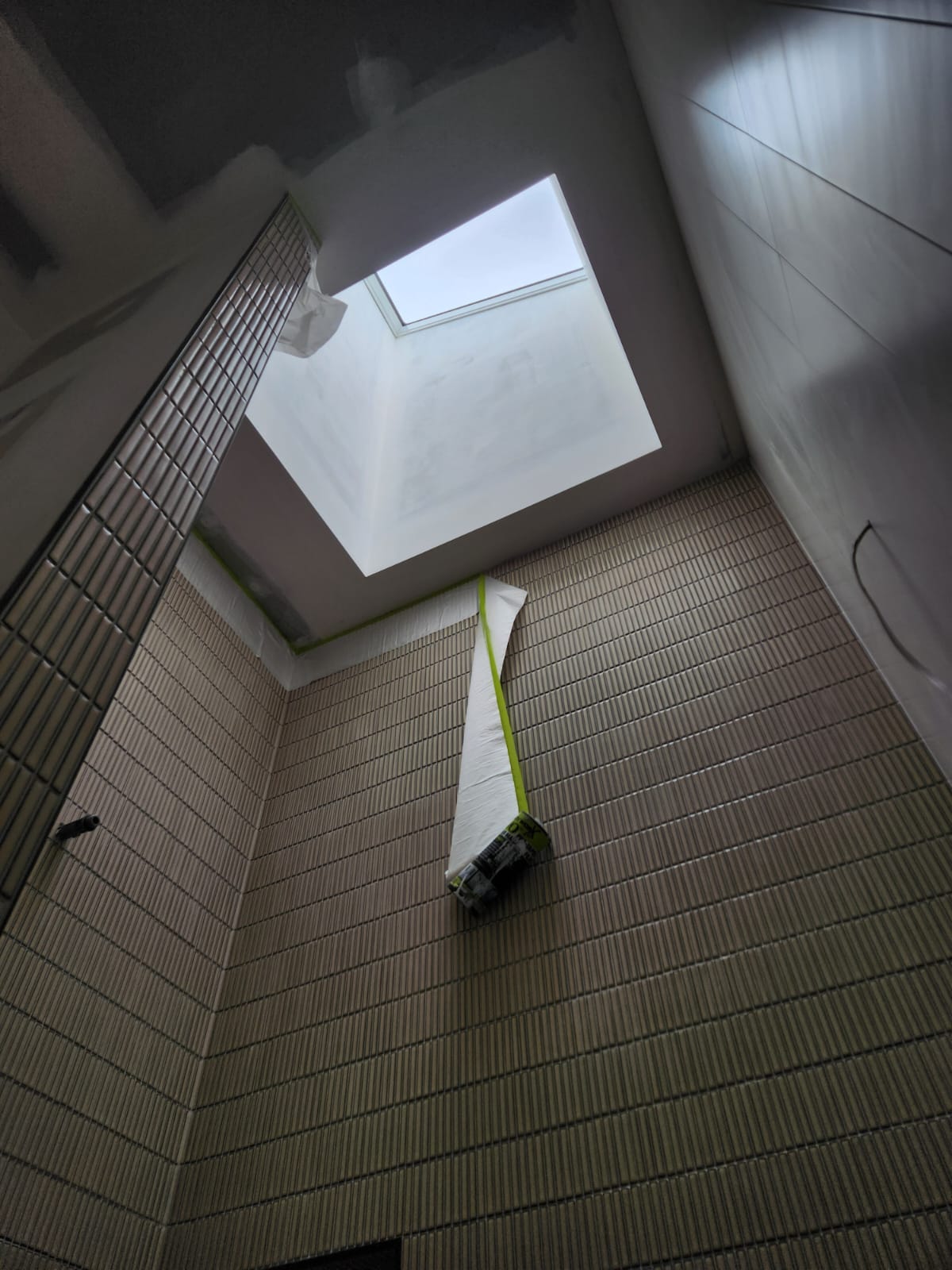 Tiled stairwell void with a skylight, masked and prepared for painting