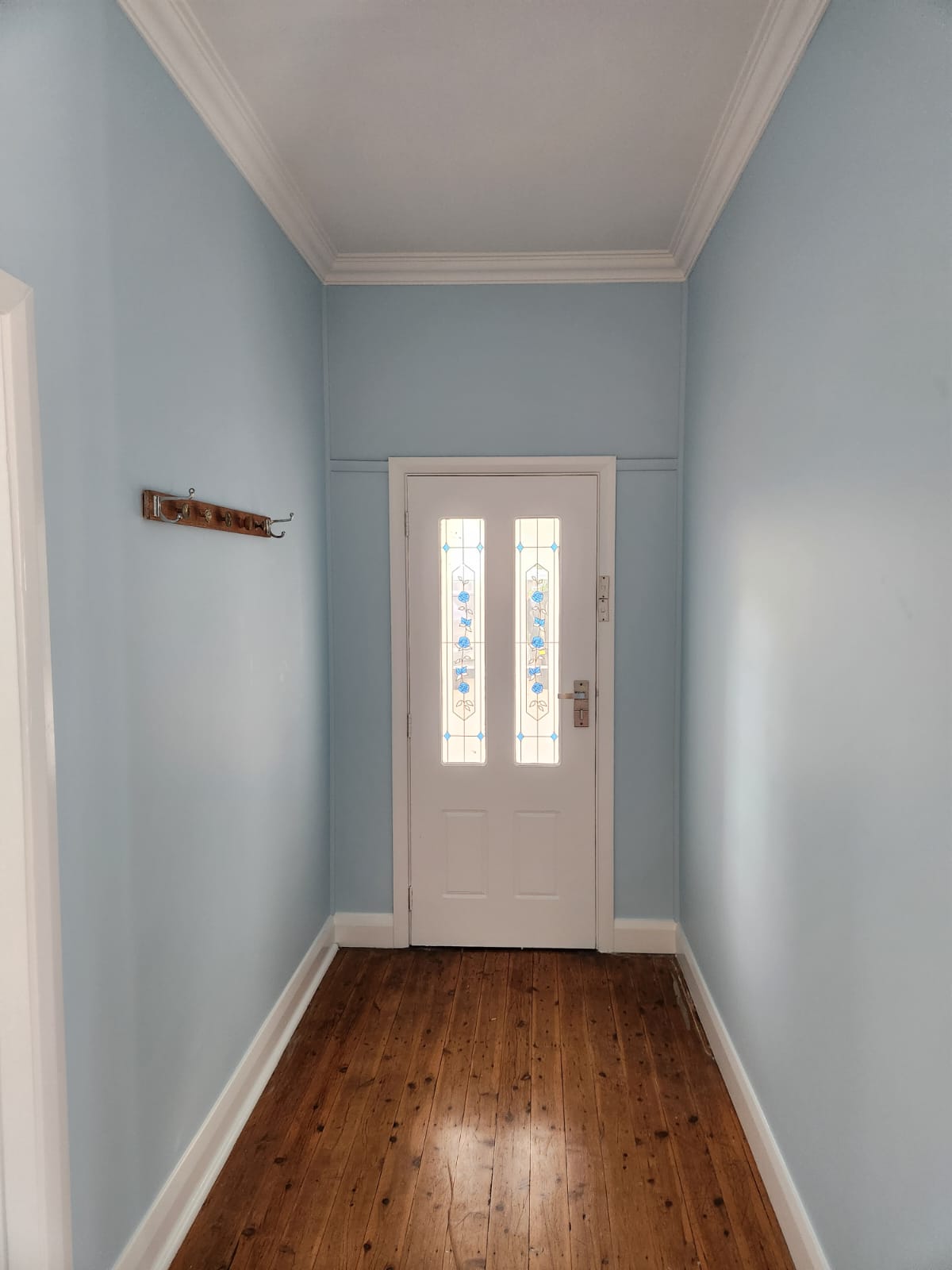 Blue hallway with white trim and a stained-glass entry door