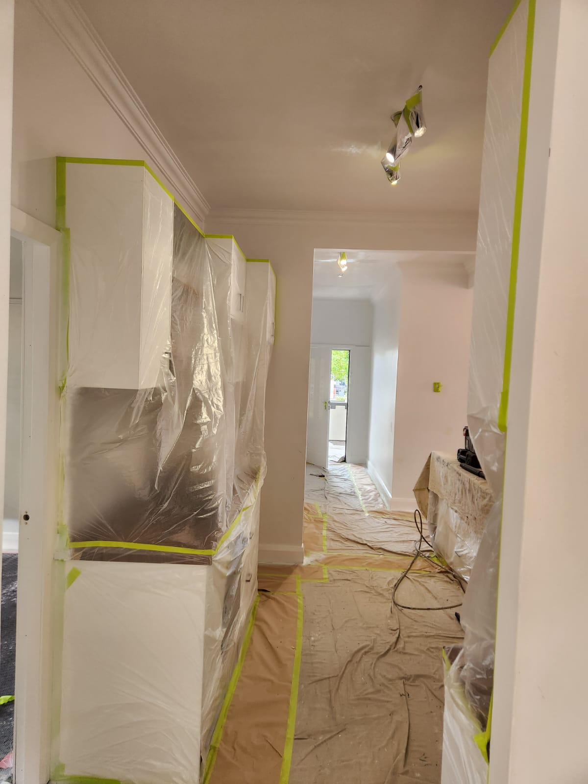 Interior hallway and kitchen wrapped in plastic and drop sheets before painting