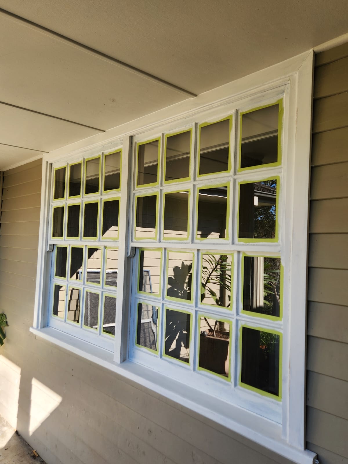 Exterior window frames masked with tape during painting preparation