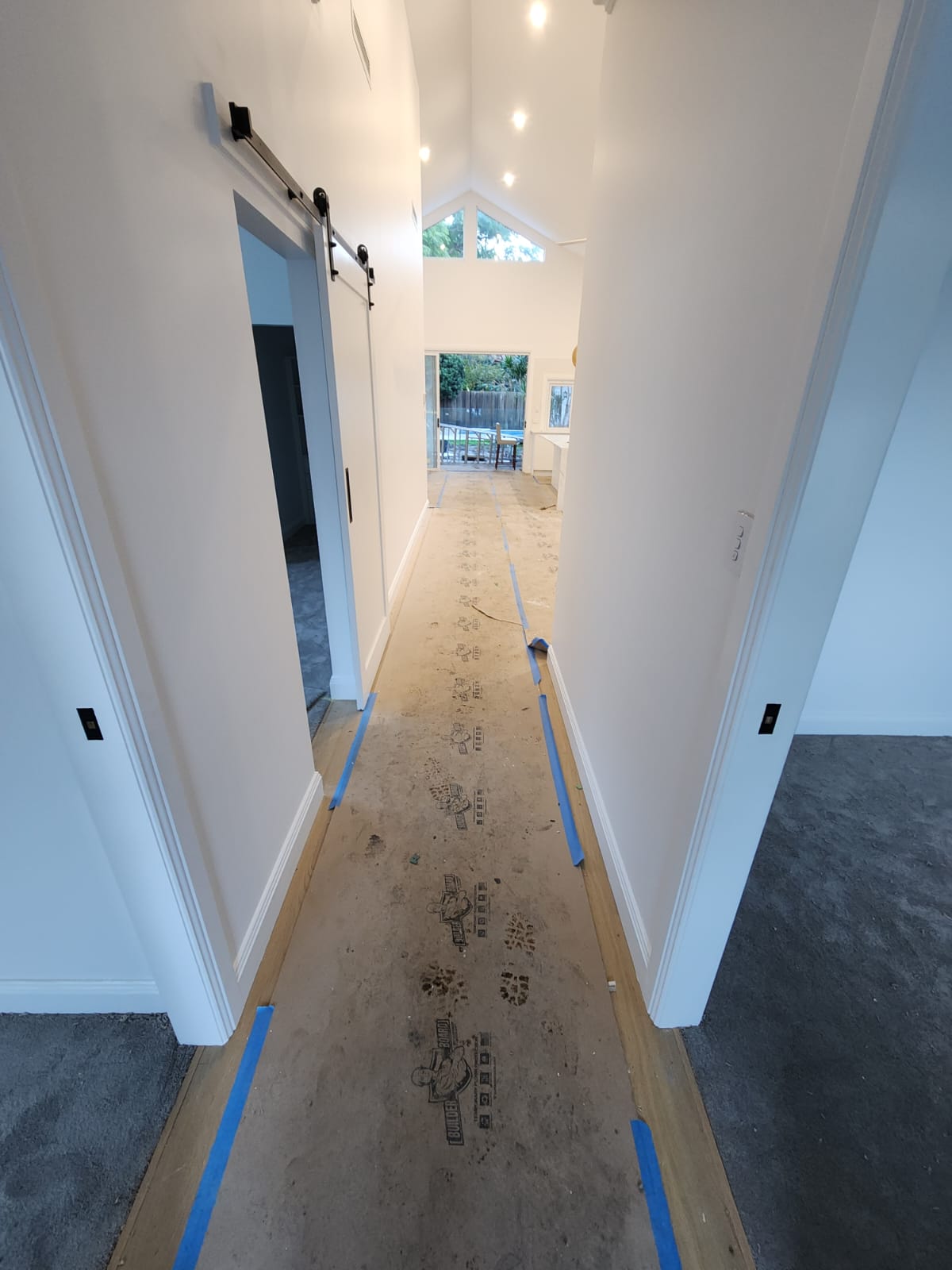 Bright hallway with a barn door and protected flooring during repainting