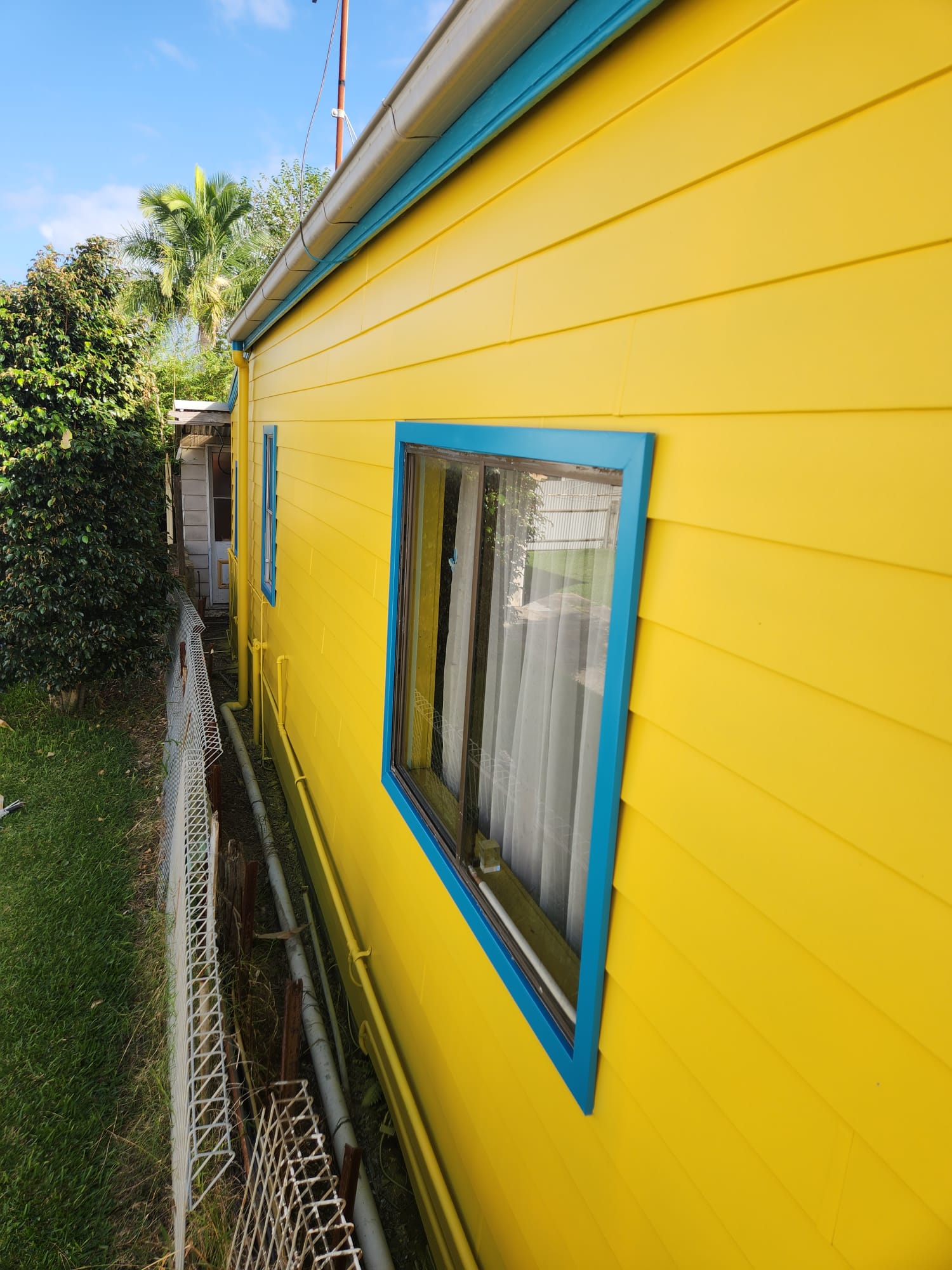 Close-up of yellow cladding and a blue-painted window frame
