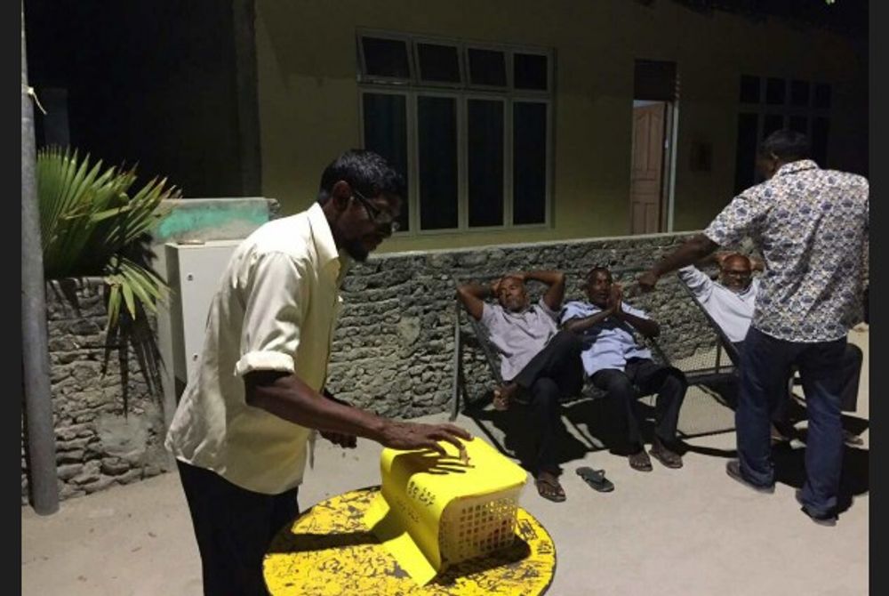 A supporter places his donation in the fund box placed in Dhevvadhoo