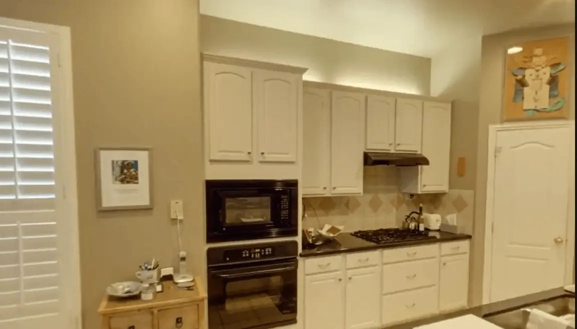 A woman wearing gloves washes a drinking glass at a kitchen sink, focusing on hygiene and cleanliness.