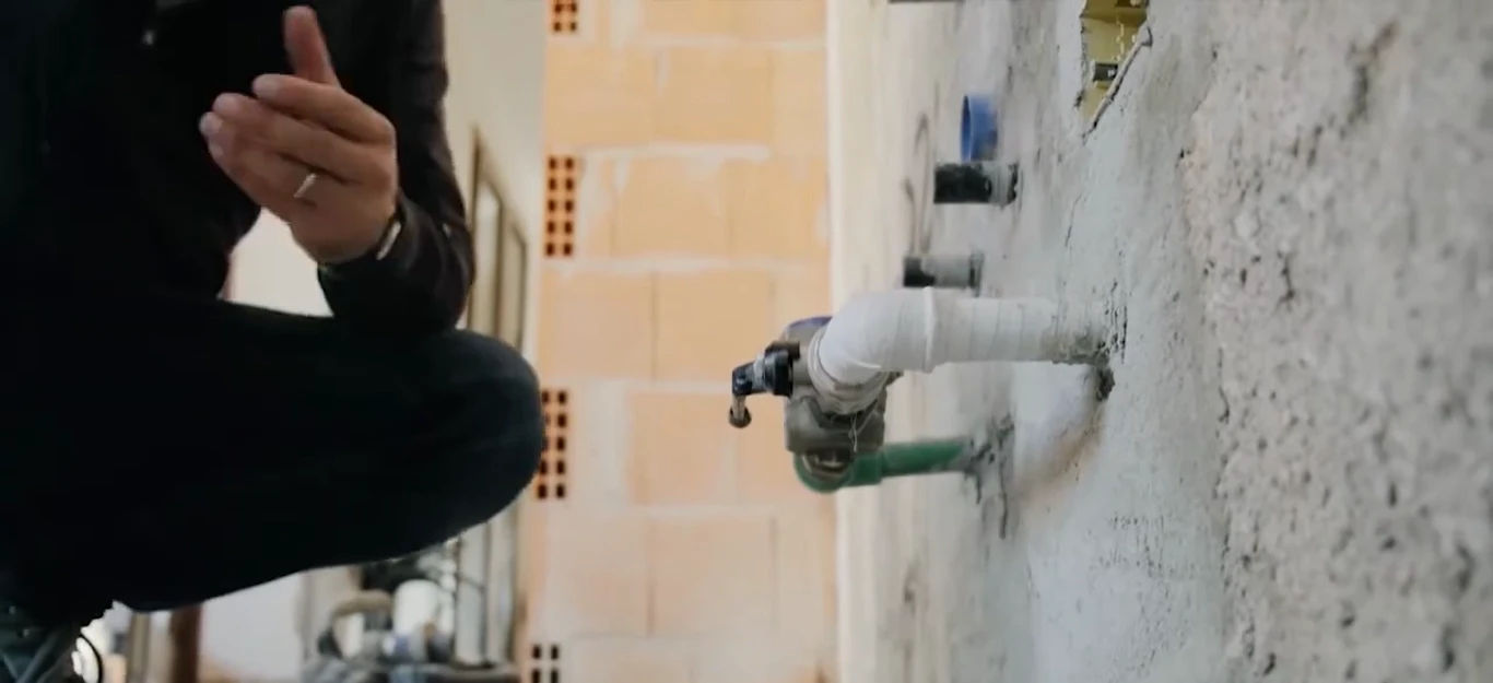 A woman wearing gloves washes a drinking glass at a kitchen sink, focusing on hygiene and cleanliness.