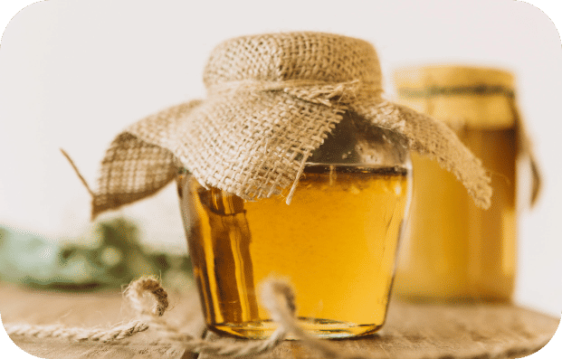 A clear, unbranded jar of fresh honey on a wooden surface