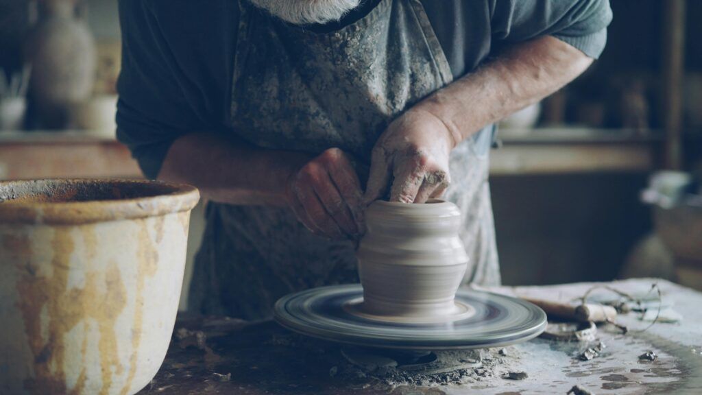 A man making some pottery on a pottery wheel using his hands