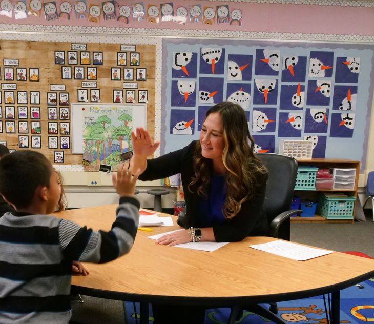 Teacher and student high five after reading instruction