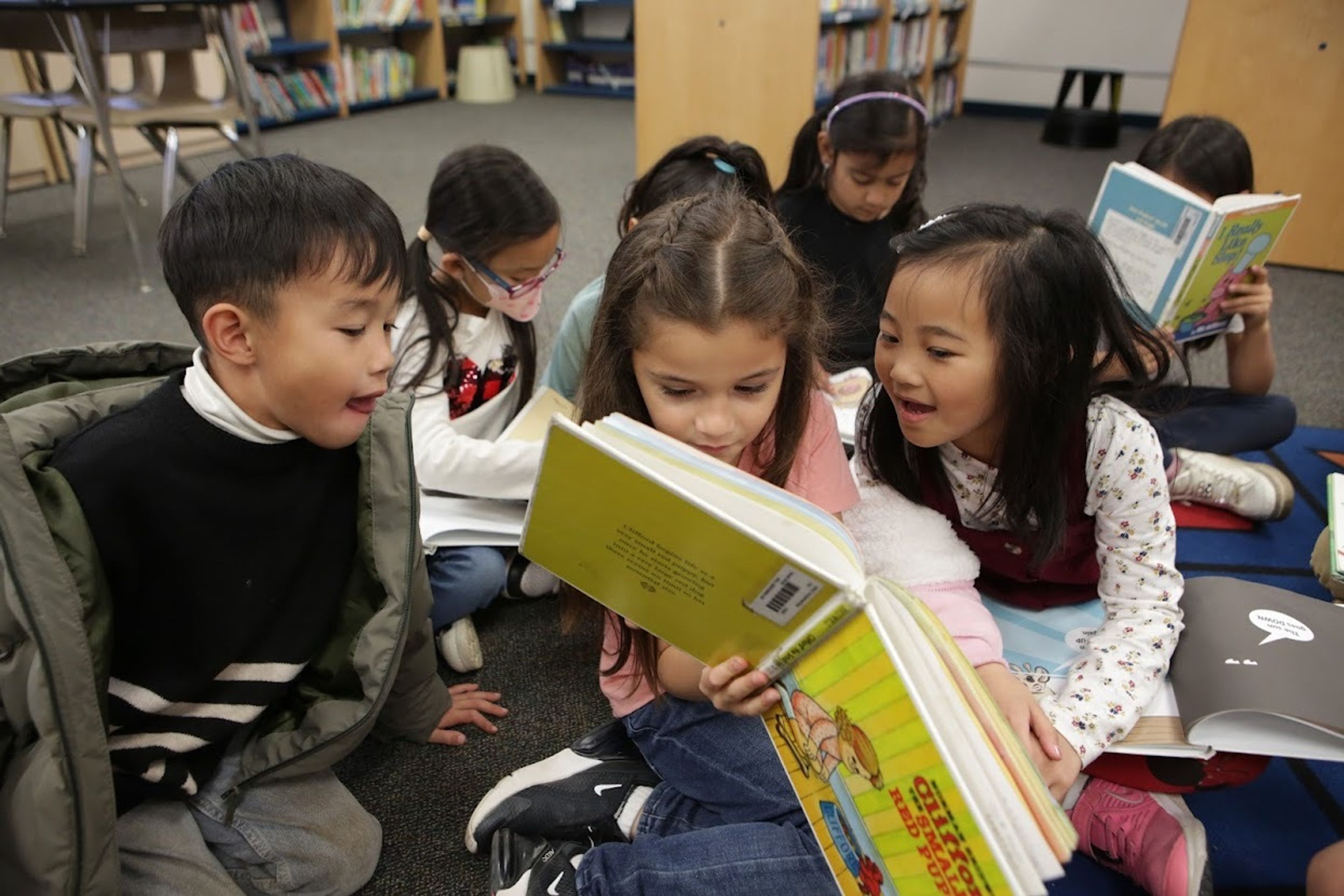A group of children looking at a book in the library