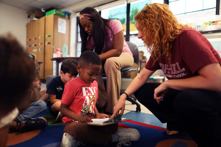 Teachers help students who are writing on clipboards