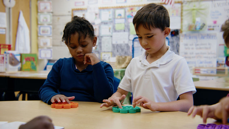 Two kids in class using popit toys for a lesson on phonemes