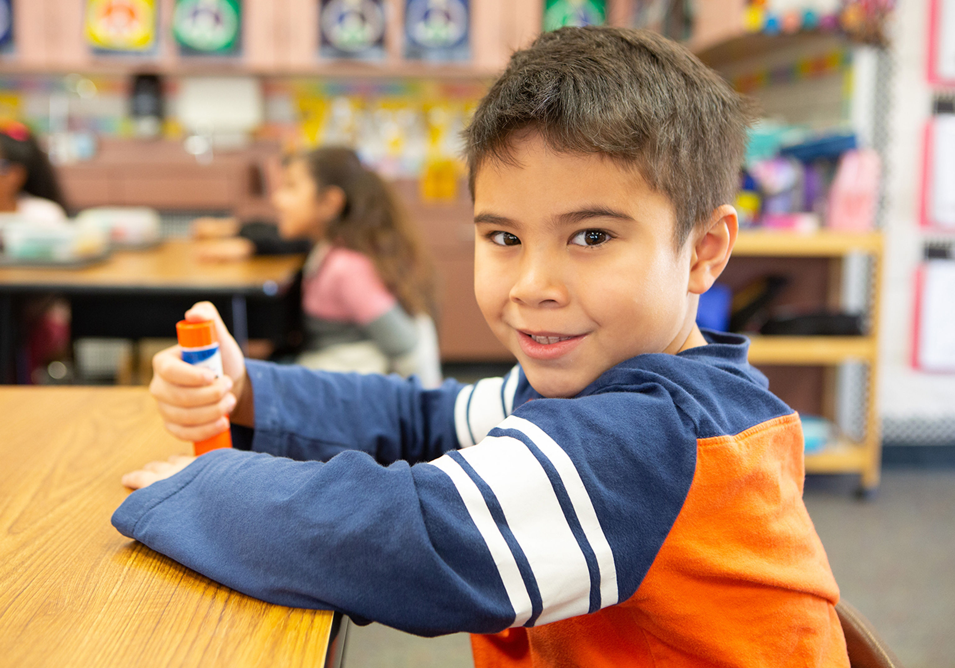 A boy sitting at his desk and smiling into the camera