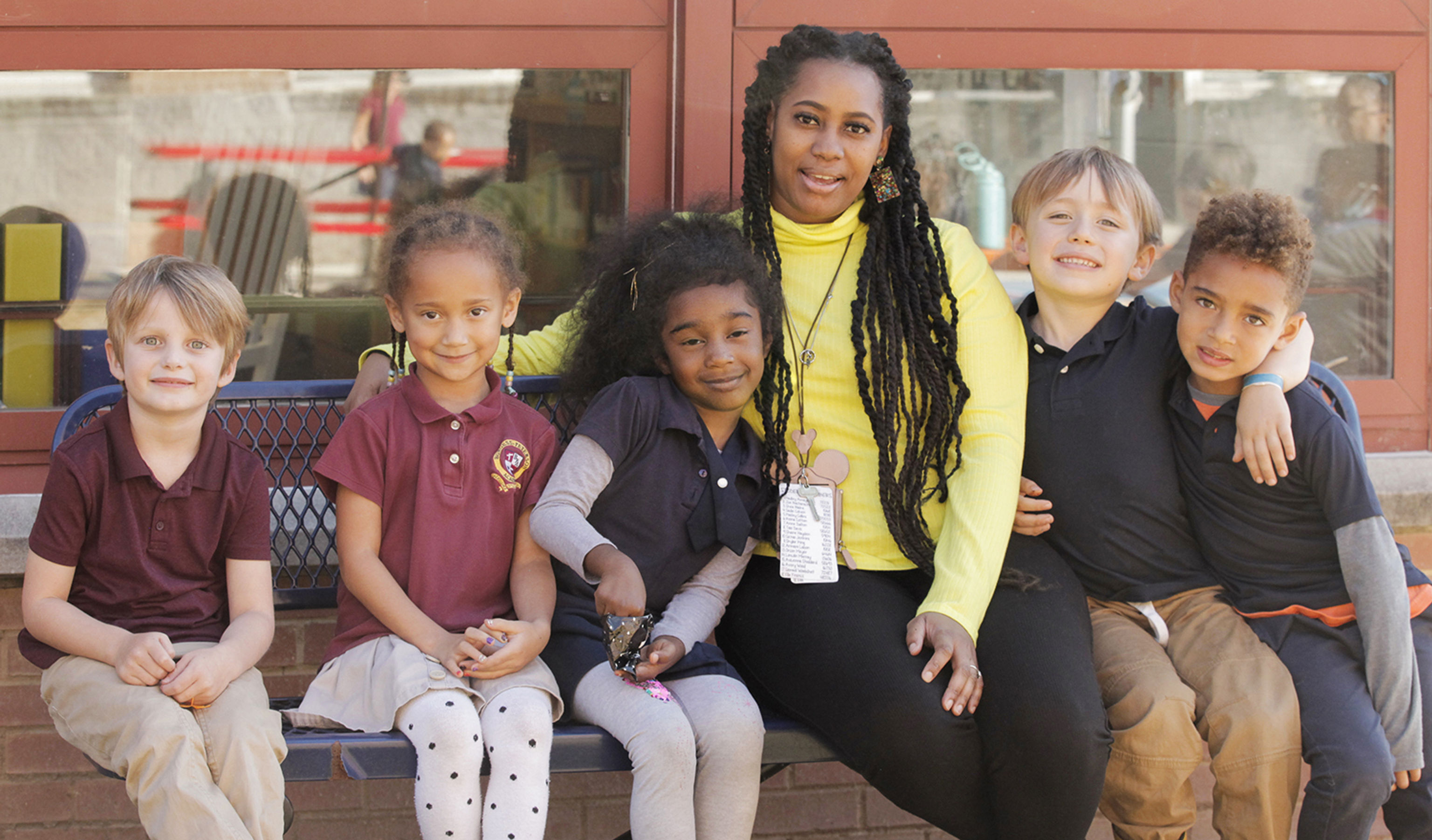 Teacher sitting on a bench outside with students