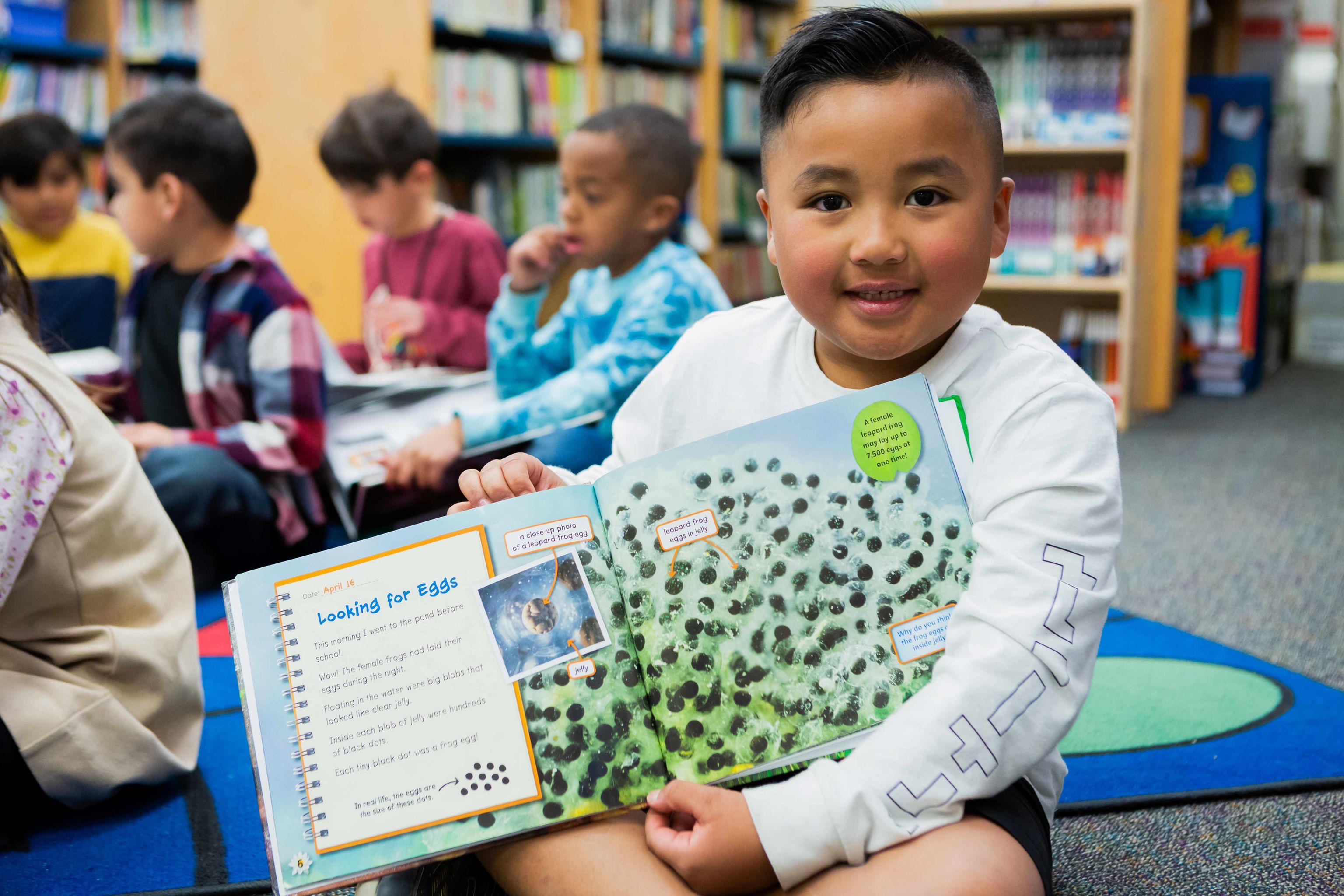 A young boy displays a book he is reading.