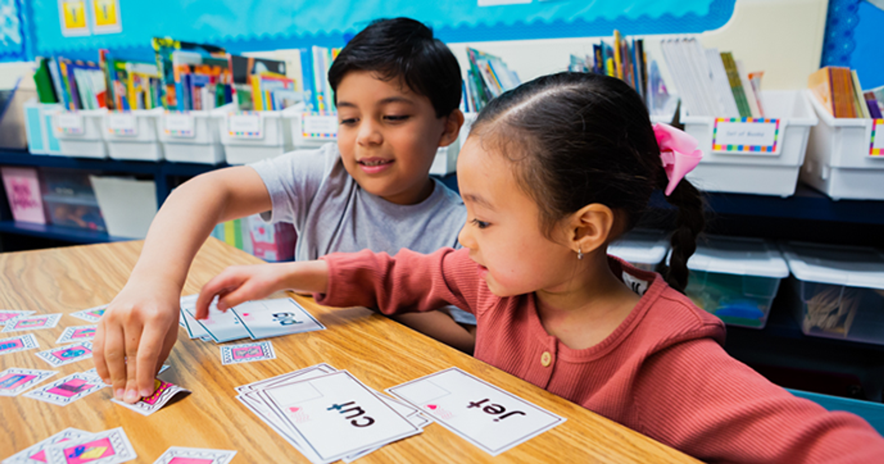 two students practice making short vowel words with cards