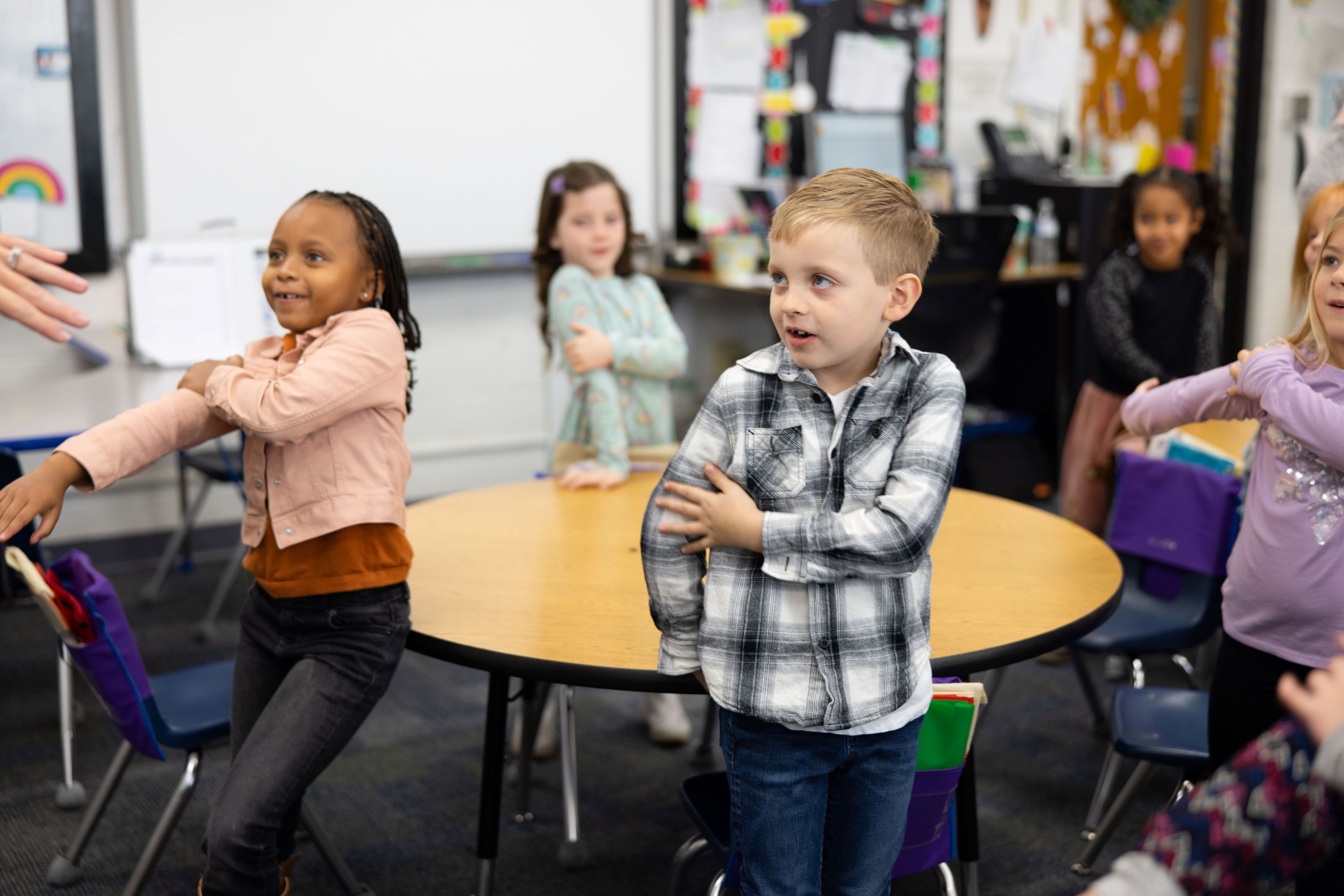 Students touching their arms while playing a rhyming game.