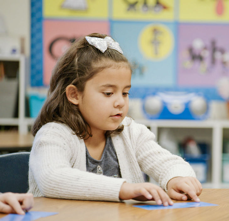 First grader pointing at card on table