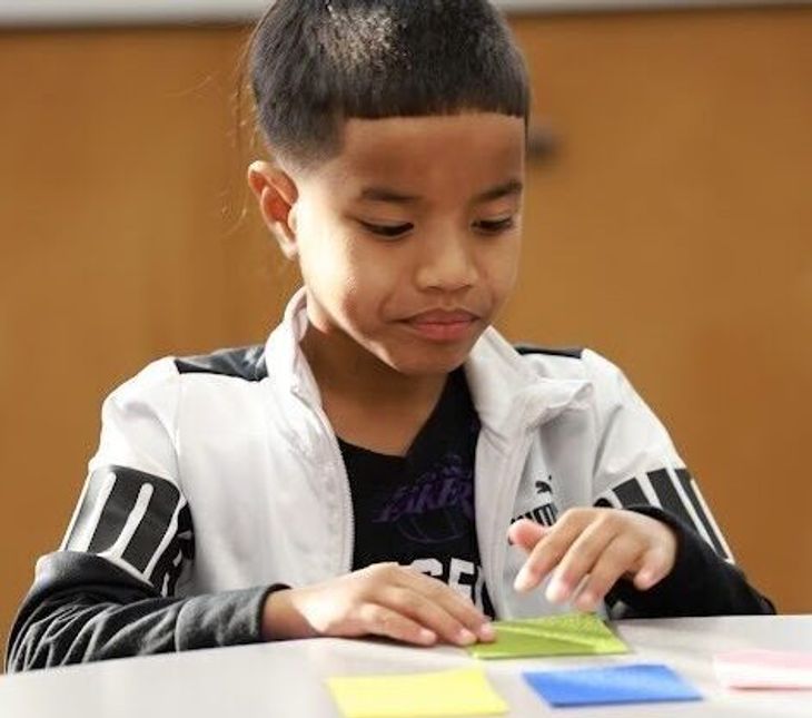 A first grade boy manipulates felt squares during small group phonemic awareness instruction.