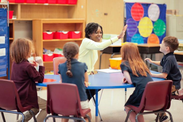 Teacher high fives first grade students in a small group