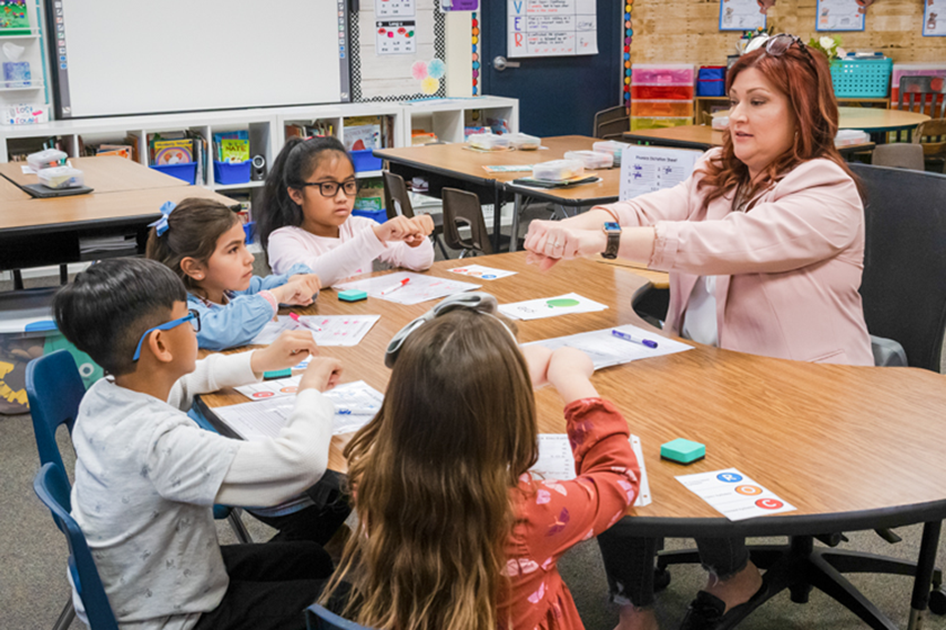 Teacher showing students how to blend syllables using their fists