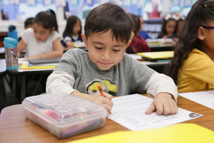 Child writing at a classroom desk