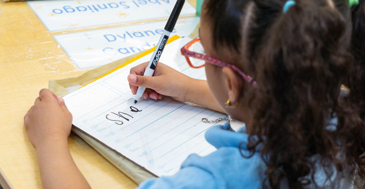 Girl writing on a wipe board in class